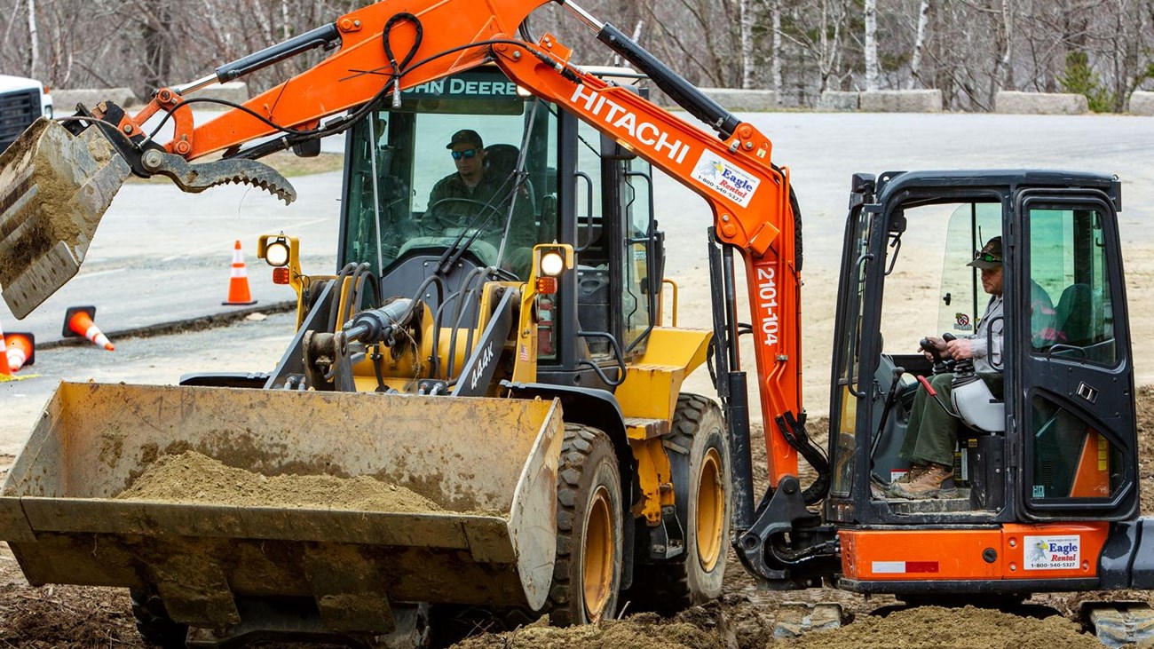 a backhoe machine digging in a parking lot