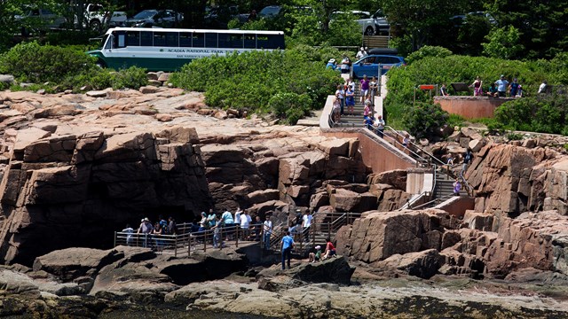 People walking down a path from road to coastline