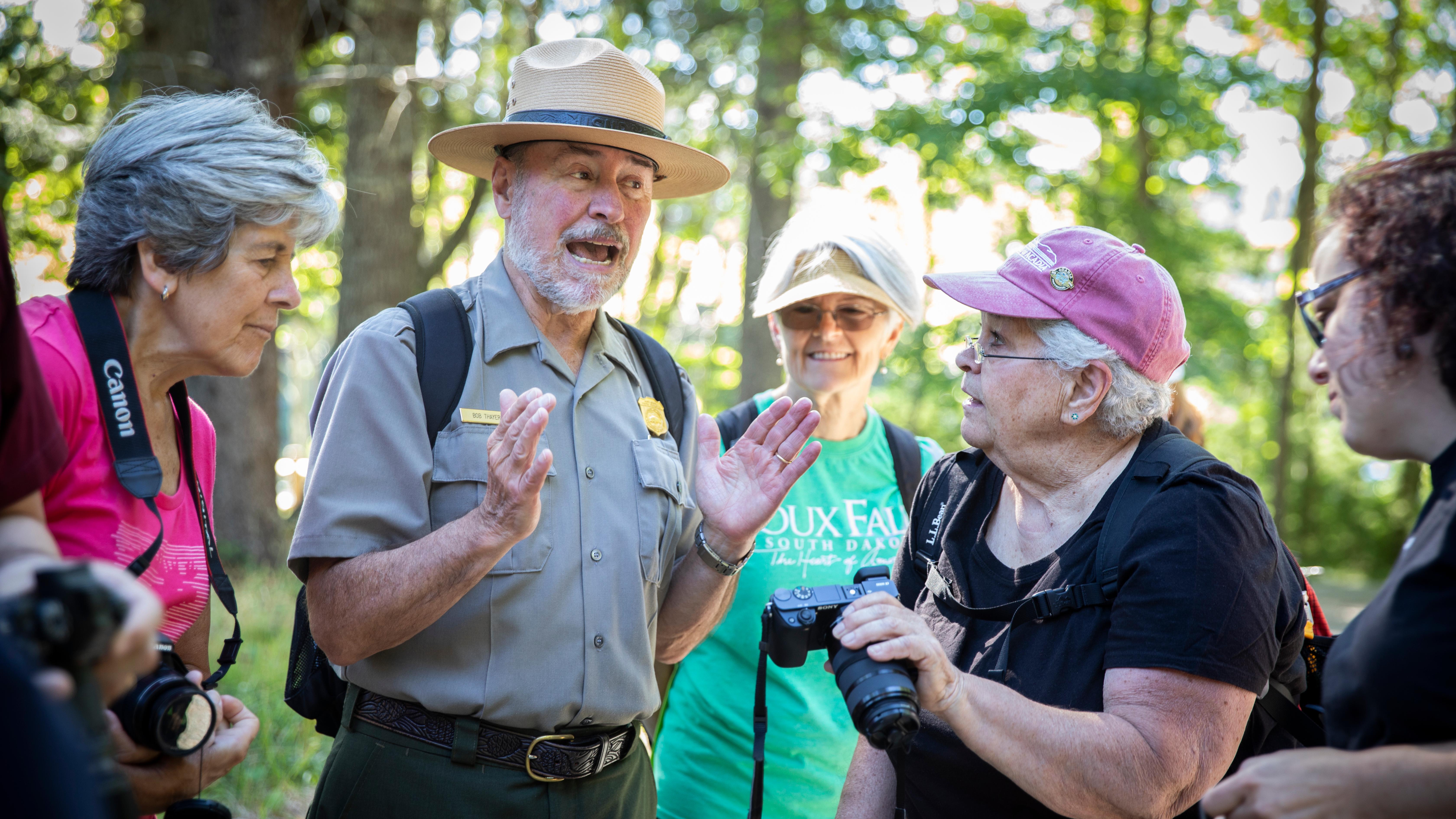 A uniformed park ranger braces appears to be in a spirited discussion with four visitors.