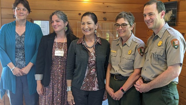 2 park staff in uniform stand with three women in plain clothes