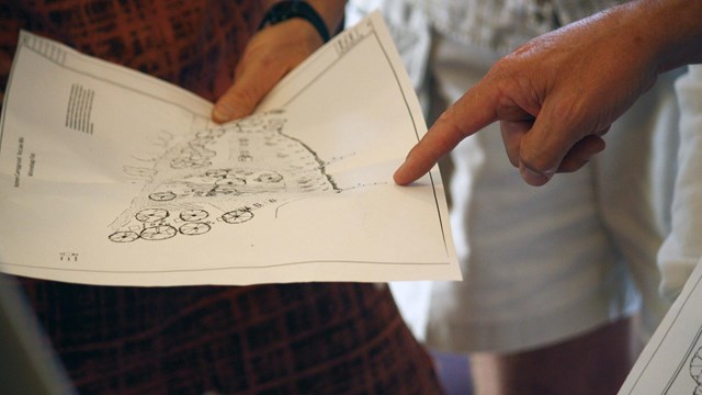 a finger points at a landscape plan