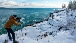 Photographer snaps portrait of man standing in snow along Atlantic coastline