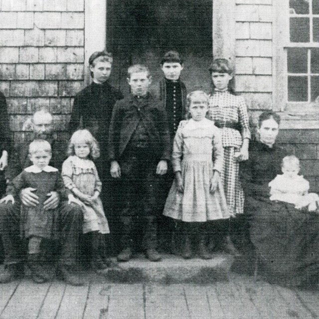 A black and white image of a large family posing in 19th century European style clothes