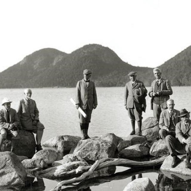 People standing on rocks near a lake