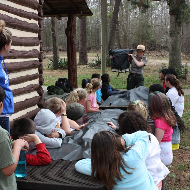 Group of children gathered around outside for a hands on ecology lesson.  