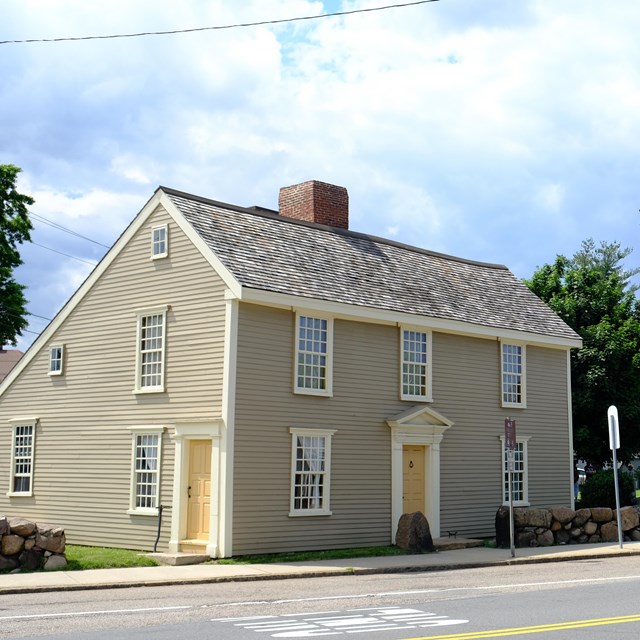 A trolley sits in front of two historic 2-story wooden homes