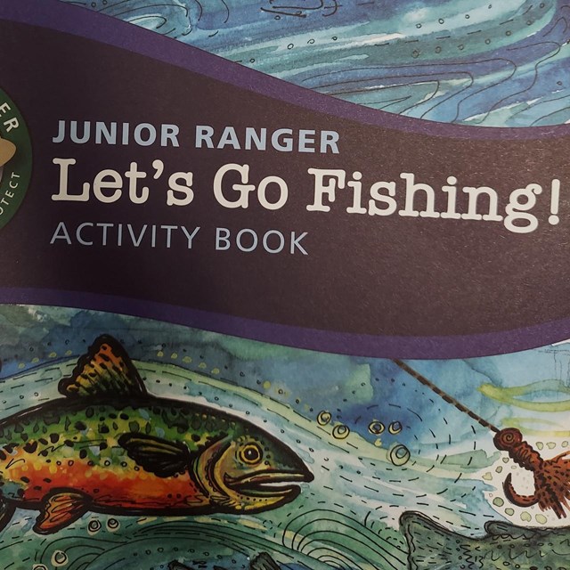 A fish swims toward a hook at the end of a rope on the cover of the junior ranger fishing book.