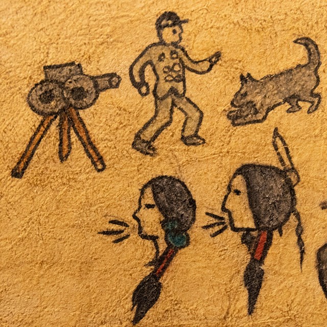 Drawing on elk hide of a movie camera and several figures, including a military unformed man & wolf