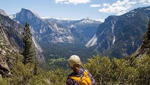 Back of hiker in foreground looking into the distance with half dome in the background