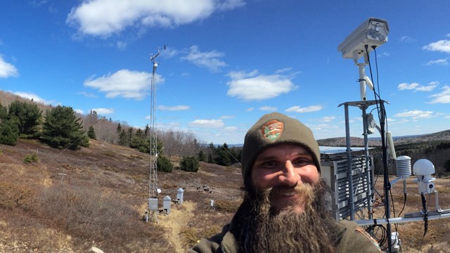 Photo of an NPS employee at the McFarland Hill air monitoring station in Acadia National Park.