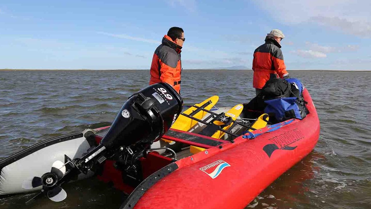 Two researchers launch a boat in an Arctic lagoon.
