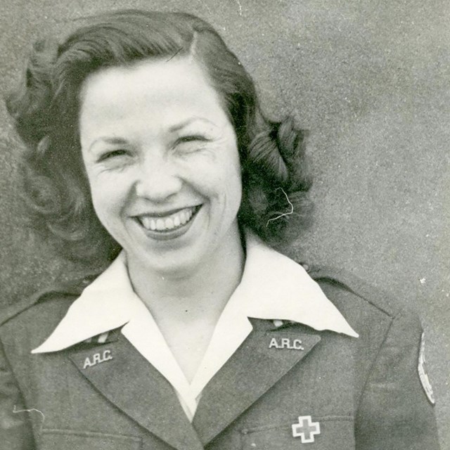 A woman in an American Red Cross uniform smiles at the camera