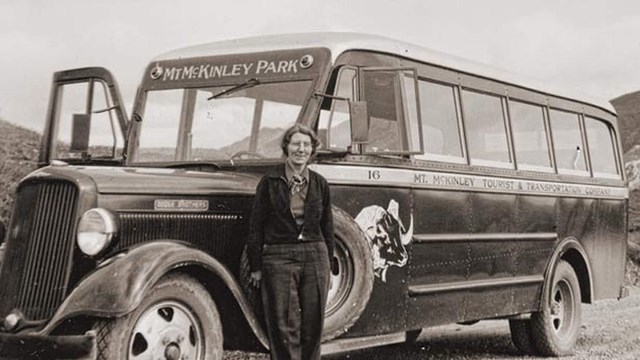 black and white historical photo of a women standing near a bus