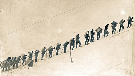 a line of hikers in the snow during the klondike gold rush