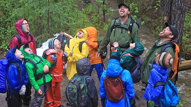 rangers stand with a group of colorfully dressed children in the rain with their tongues out