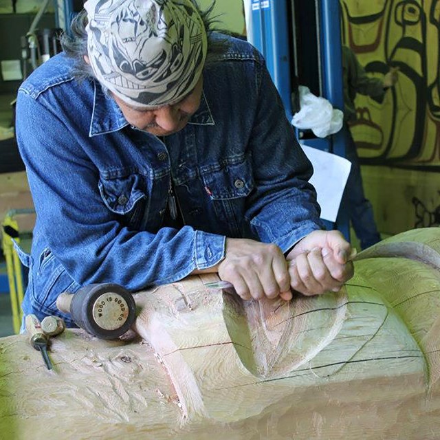 A man is carving a large piece of wood.