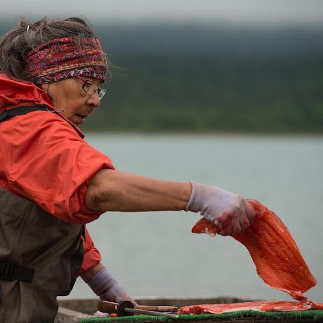 A women in waders prepares a cut of salmon