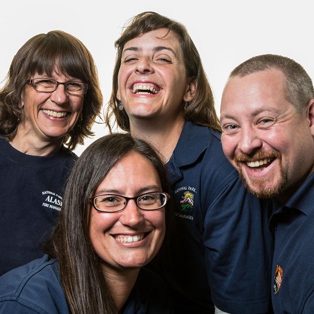 Three women and one man all smiling, crowded in together wearing matching t-shirts.