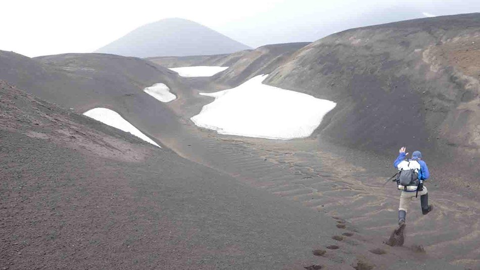 A man bounds across volcanic dunes.