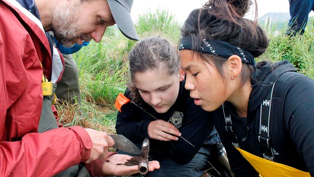 Youth look closely at a soil core.