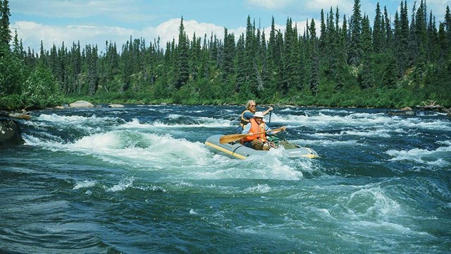 Two men raft through whitewater rapids.
