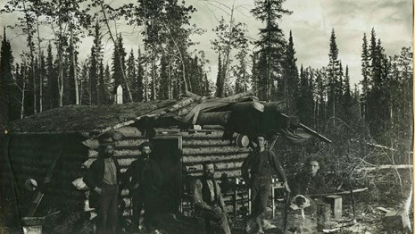 Historical photo of miners at a cabin,