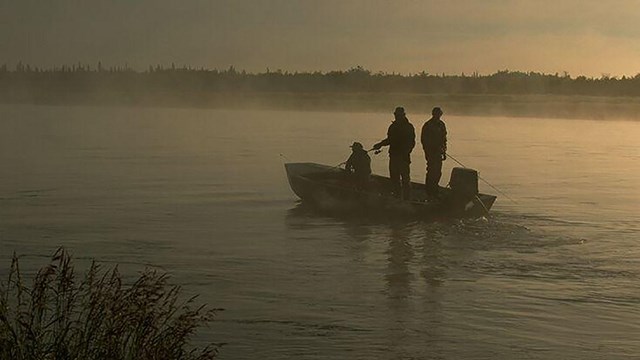 Three men fishing in a boat.
