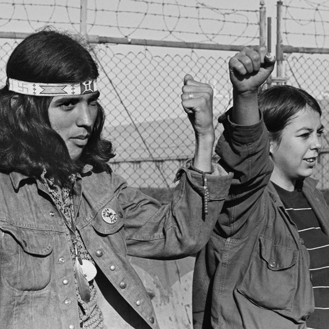 Two indigenous college students raise their fists in solidarity.