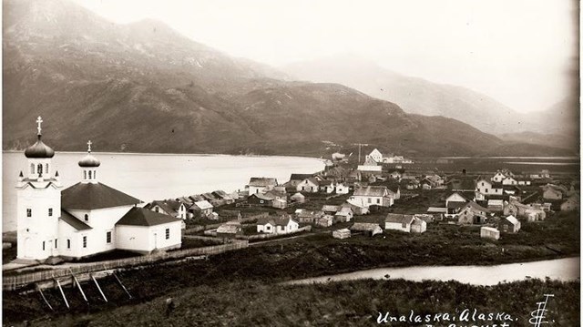 a town along a beach with a large russian church on the far left