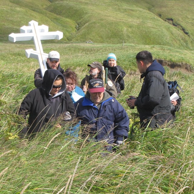 People in a grassy field with a Russian cross