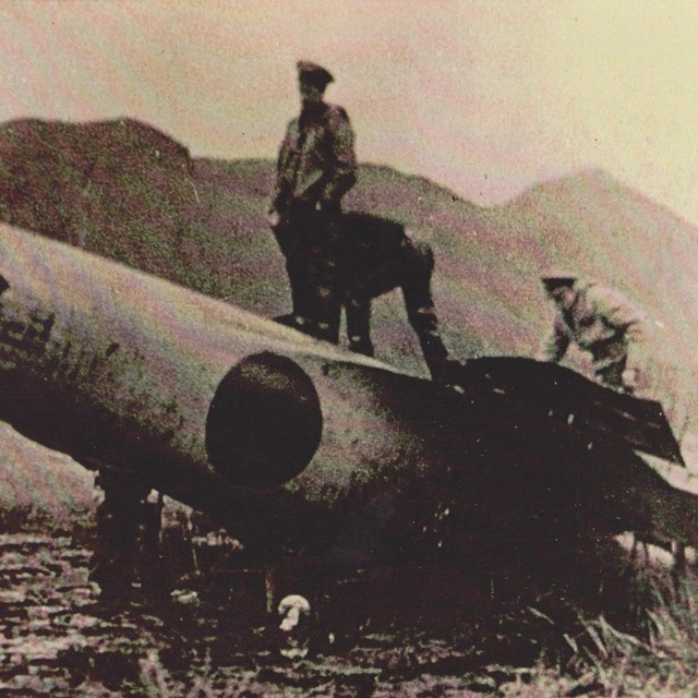 men standing on a crashed japanese fighter plane