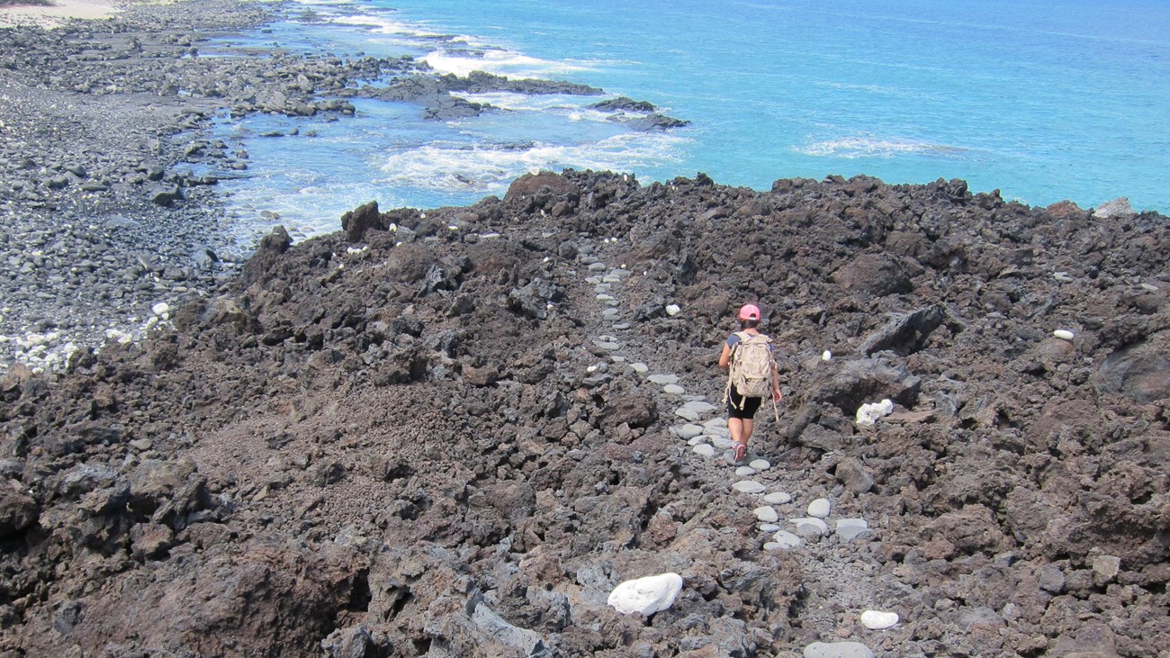 Woman descending a rock trail along the ocean coast
