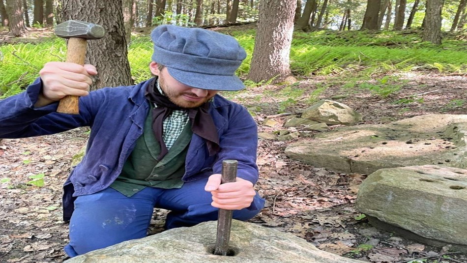 A park ranger in period clothing giving a stone cutting demonstration. 