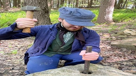 A costumed ranger performing a stone cutting demonstration.