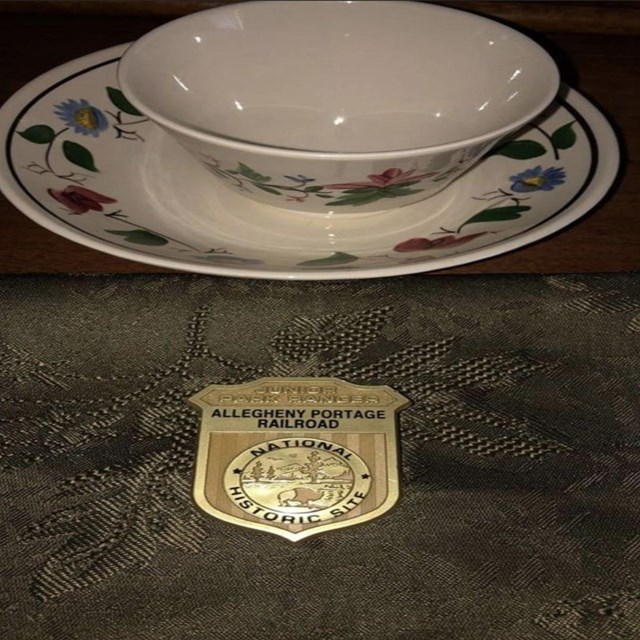 A period cup on a table with a Junior Ranger badge. 