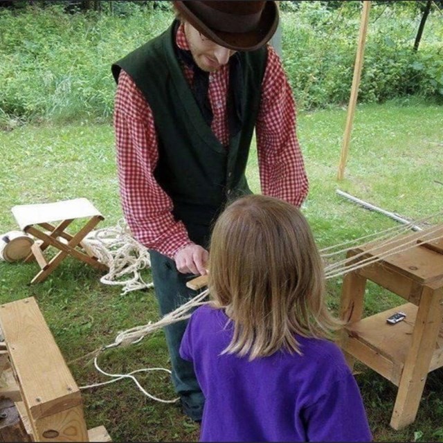A park ranger in period clothing presents a rope making demonstration. 