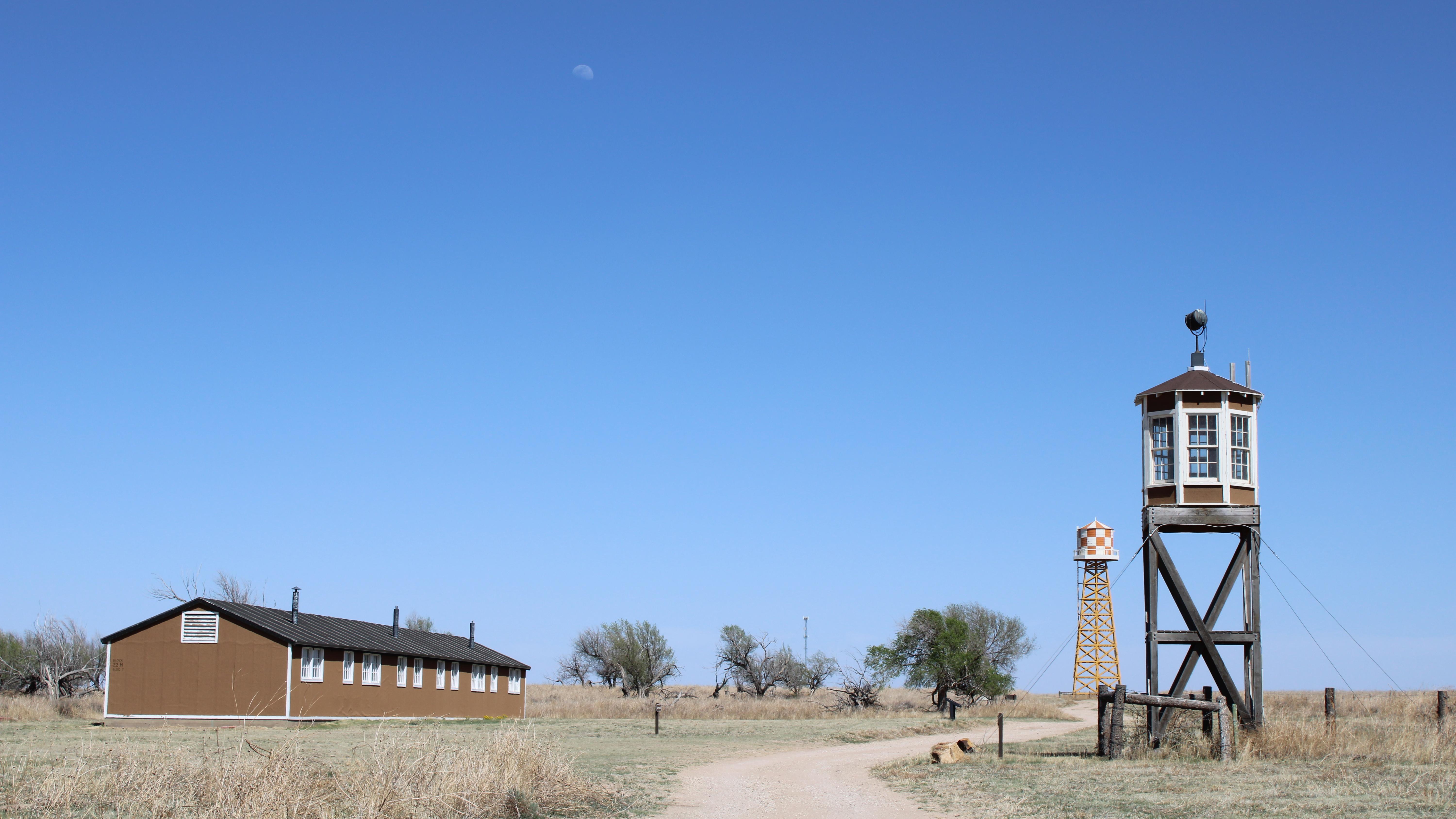 A road weaves between a guard tower and barrack. A water tower is in the background.