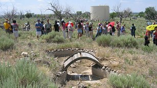 Image from annual pilgrimage, group of people explore and walk through historic garden. (amache.org)