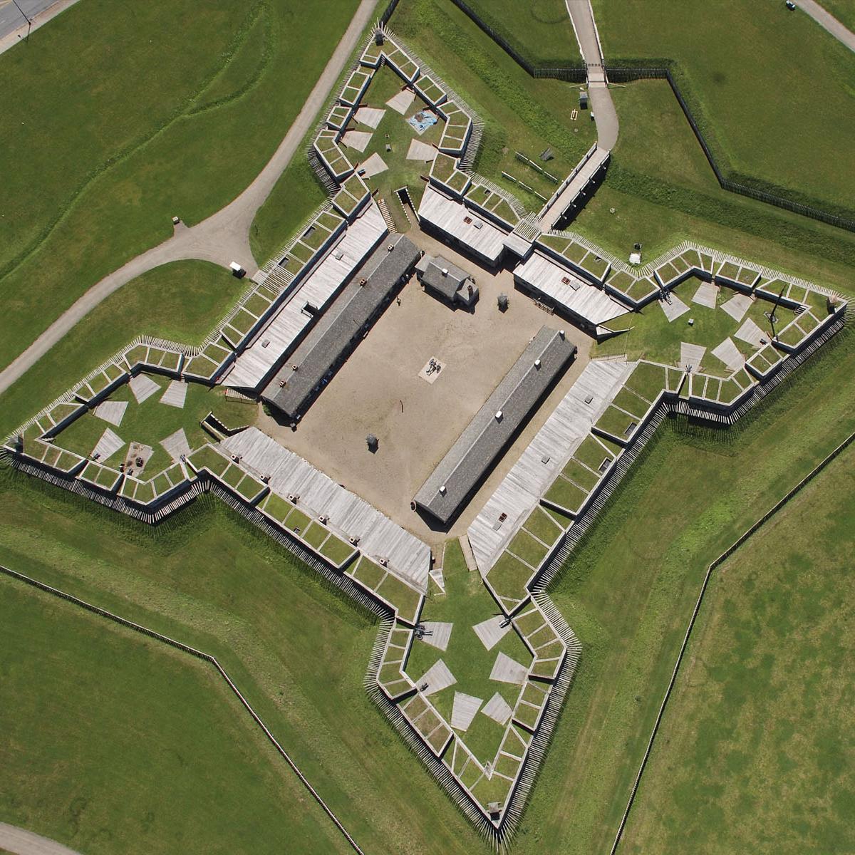 A view of the fort from above. A wooden star-shaped building sits in the middle of a grass field.