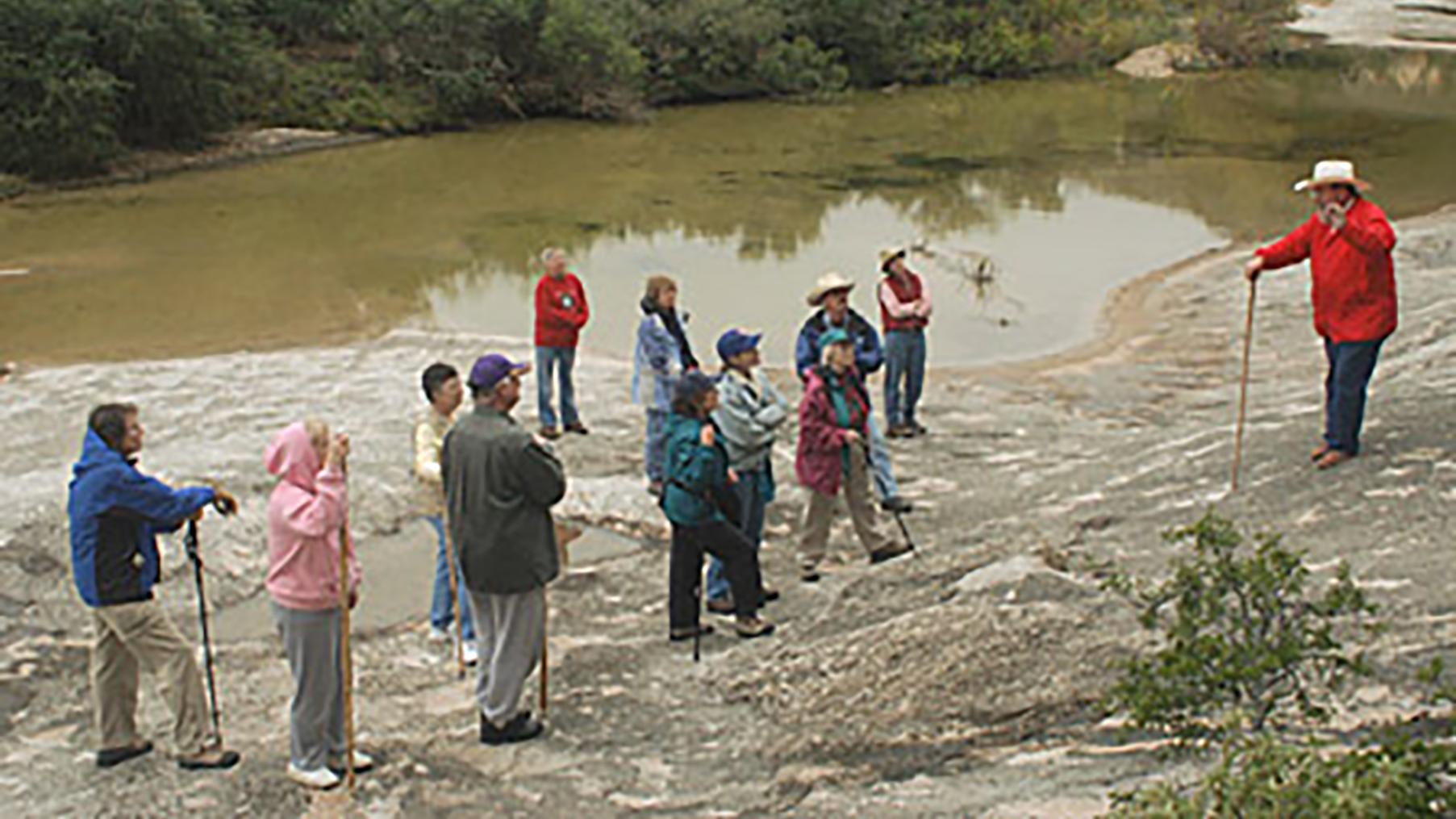 Tour guide providing a guided trail experience on the shore of a river.