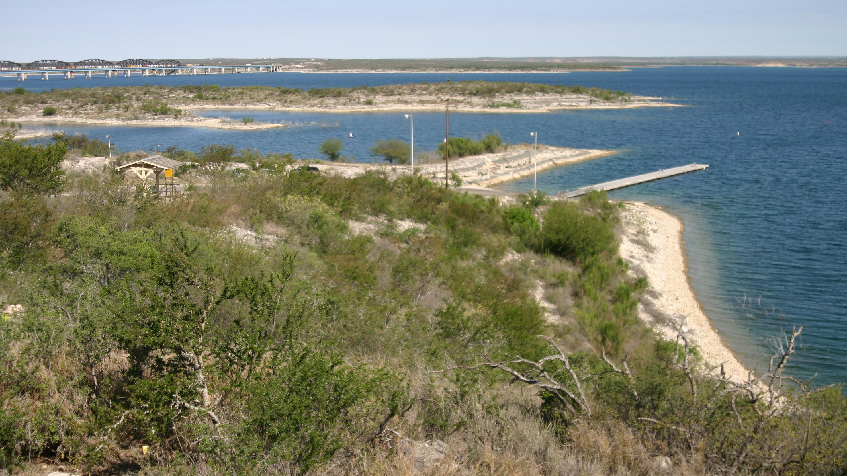 View of a boat ramp, lake and bridge in the distance.