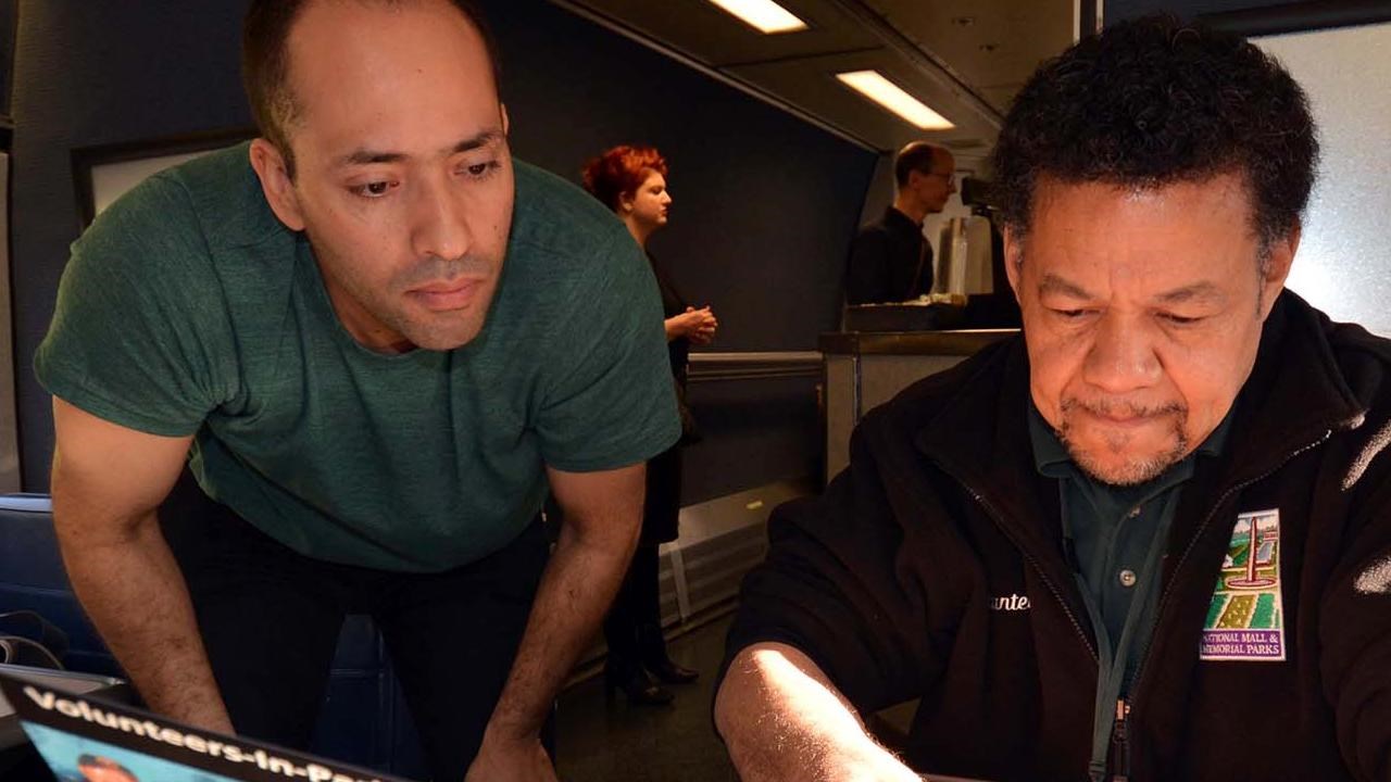 A volunteer helps a train passenger find information on board Amtrak