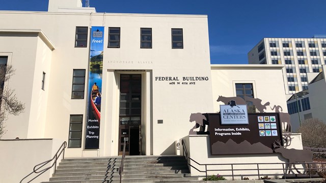 Large sandstone building with sign with metal wildlife and logos out front.