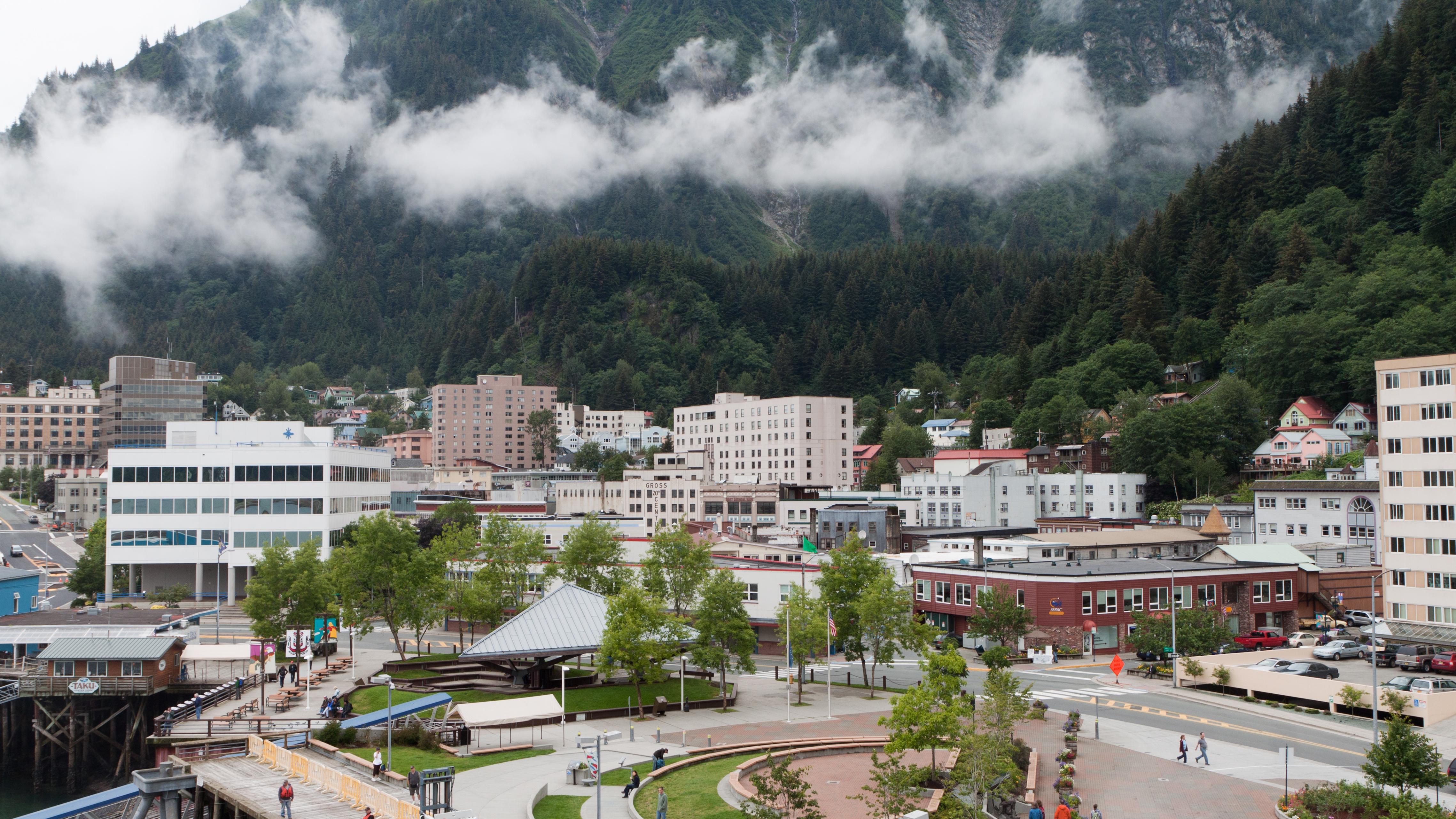 Small skyline of buildings with tall green mountains rising behind.