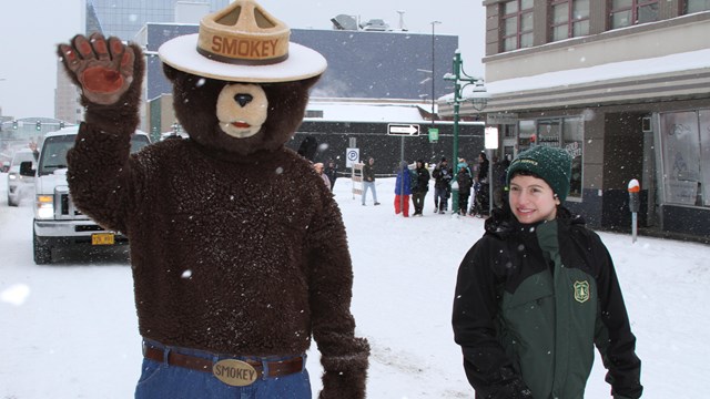 Smokey Bear and Forest Ranger walking in snow. 