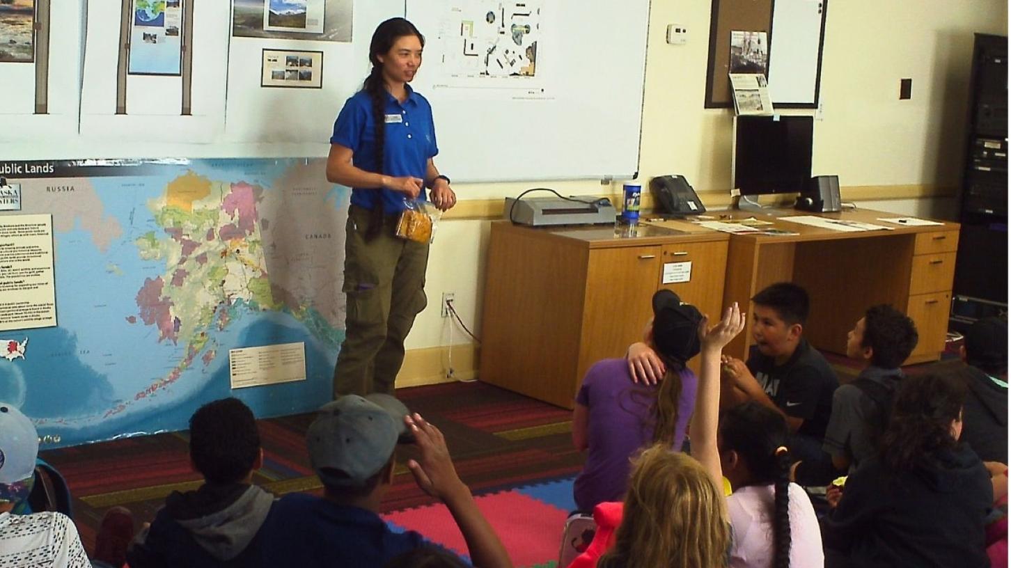 Teacher instructing class with Alaska Public Lands map behind her