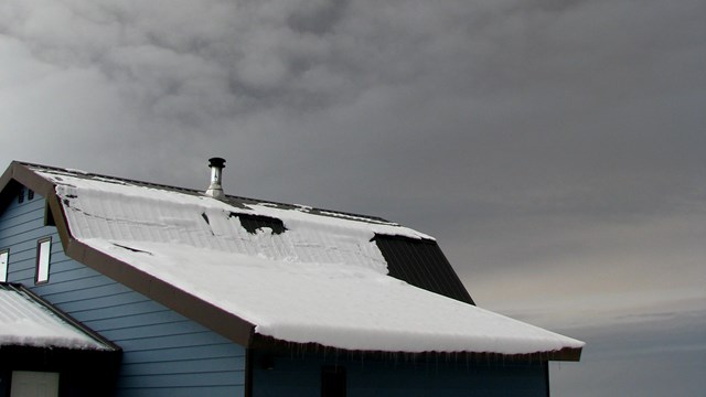 Cloud of ash above a small house.