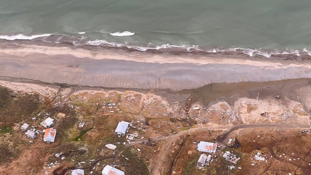 Aerial photo of shoreline with houses along coastal edge.