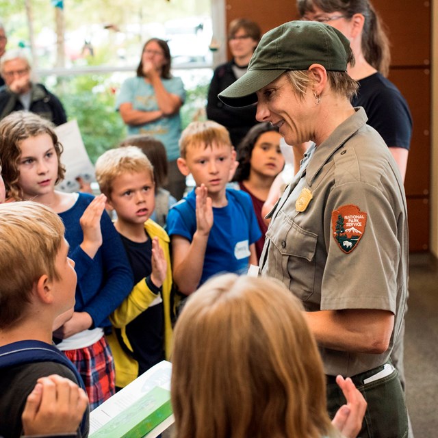 Students gather around a park ranger to learn. 