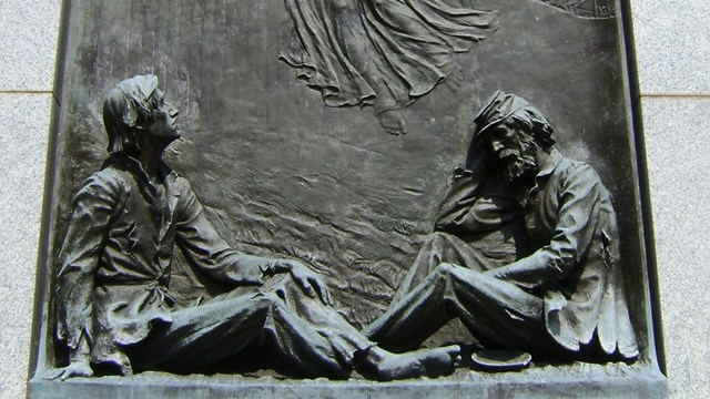 A bronze plaque with an angel above two imprisoned Civil War soldiers